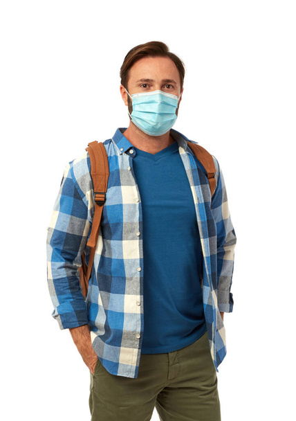 Casual man with backpack wearing a face mask on white background - Foto, Bild