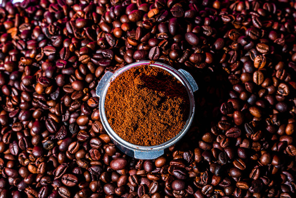 Fondo con café molido en portafilter rodeado de granos de café tostados, - Foto, imagen