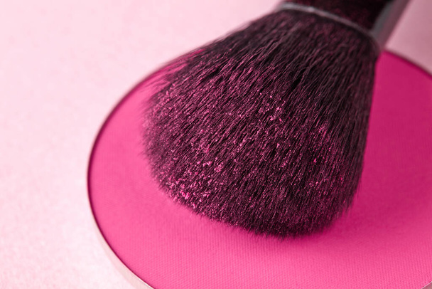 Cepillo y maquillaje en polvo sobre fondo rosa - Foto, imagen