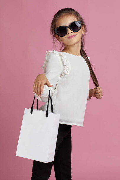 child girl in sunglasses is holding shopping bags - Φωτογραφία, εικόνα