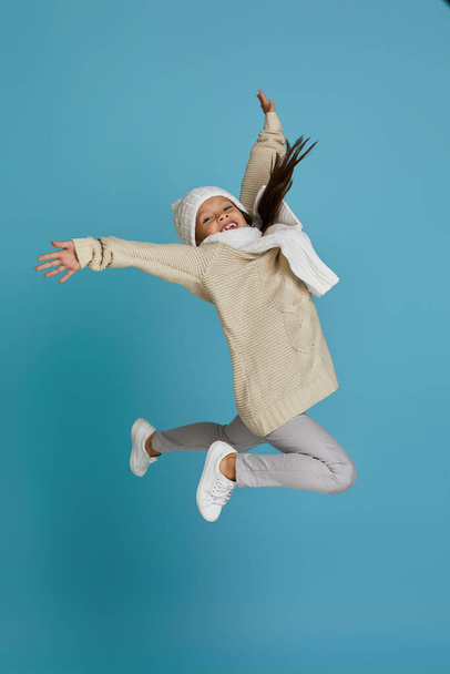 little child girl in winter knitted hat and sweater jumping - Φωτογραφία, εικόνα