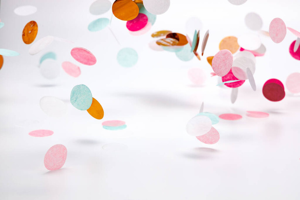 confettis tombants dans les couleurs rose, menthe et rose faits de grands cercles de papier de soie sur fond blanc avec des ombres claires. - Photo, image