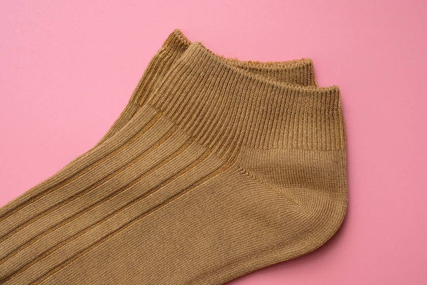 Cotton socks on a pink background top view. Short brown socks, elastic band close-up. Soft socks for sports. - Photo, Image