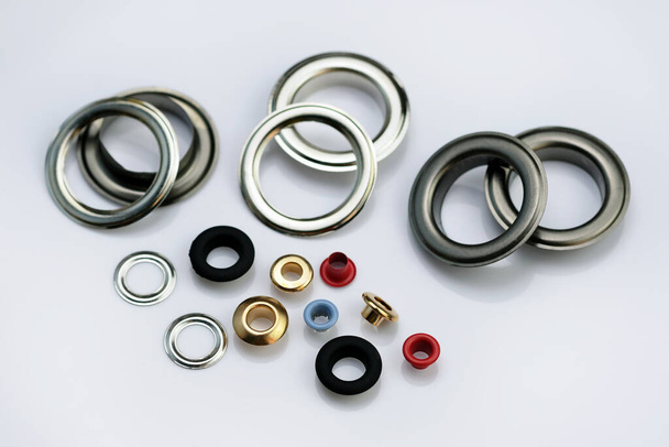Eyelets for the manufacture of banners, awnings, tents, clothes, bags, shoes. A set of multi-colored eyelets in different colors and sizes. metal elements for installation on garments. - Photo, Image