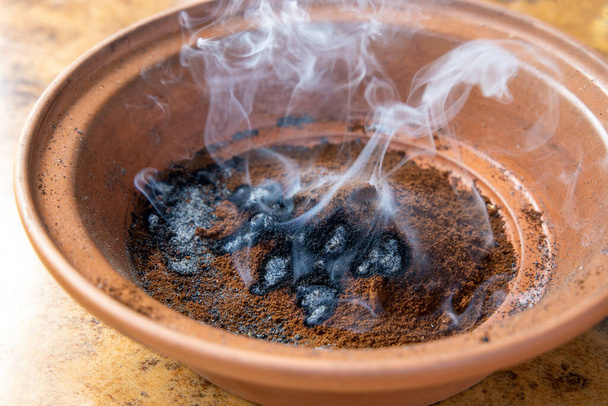 Bruciare fondi di caffè per zanzare e vespe repellenti in ciotola di argilla producendo fumo di caffè bruciato per bandire gli insetti. - Foto, immagini