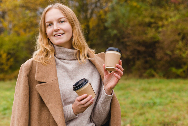 Woman holds two paper coffee cups. Take away or delivery concept. Copy space. Autumn lifestyle. Place for your text or logo on mug - Foto, imagen