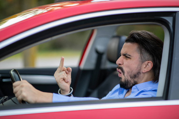 Angry driver shouting and showing middle finger while driving - Foto, Bild