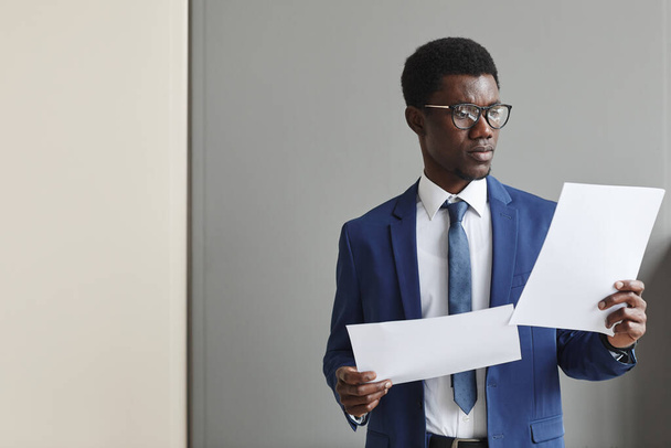 Empresário africano em vestuário formal que examina o contrato contra a parede cinzenta - Foto, Imagem