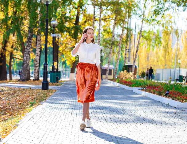 Portrait of a young beautiful business girl walking on summer street - Fotó, kép