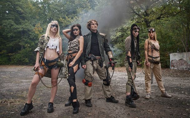 Skupina mladých lidí v roztrhaných šatech po apokalypse. Kouř, grunge, řetězy, agresivní bojový make-up - Fotografie, Obrázek