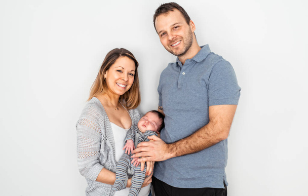 Woman and man holding a newborn Portrait of young smiling family with newborn on the hands. - Valokuva, kuva