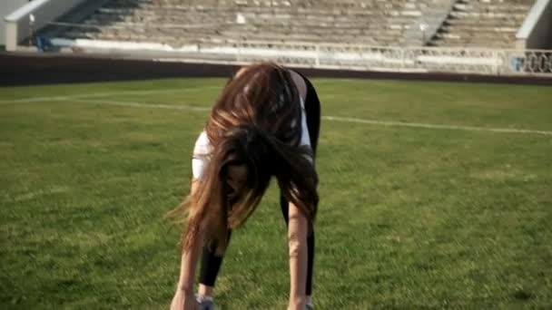jeune asiatique femelle dans sportswear étirement corps à stade champ sur sunny jour - Séquence, vidéo