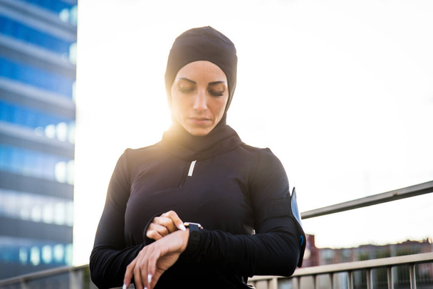 Muslim sportive girl with fit body training outside - Beautiful woman with hijab doing some sport exercises, concepts about health, lifestyle and functional training - Foto, Imagem
