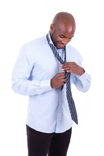 Portrait of a young African American business man knotting a tie - Фото, изображение
