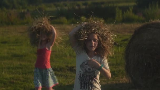 Δύο κορίτσια παίζουν με σανό στον καλοκαιρινό ήλιο. Ξέγνοιαστο καλοκαίρι. Υψηλής ποιότητας υλικό FullHD. Αργή κίνηση - Πλάνα, βίντεο