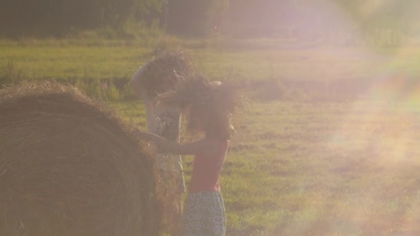 Δύο κορίτσια παίζουν με σανό στον καλοκαιρινό ήλιο. Ξέγνοιαστο καλοκαίρι. Υψηλής ποιότητας υλικό FullHD. Αργή κίνηση - Πλάνα, βίντεο