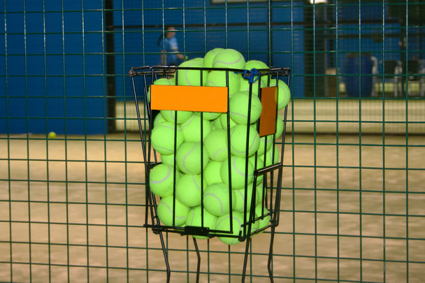 Koszyk z piłkami tenisowymi do treningu na korcie tenisowym.Tenis i padel. - Zdjęcie, obraz