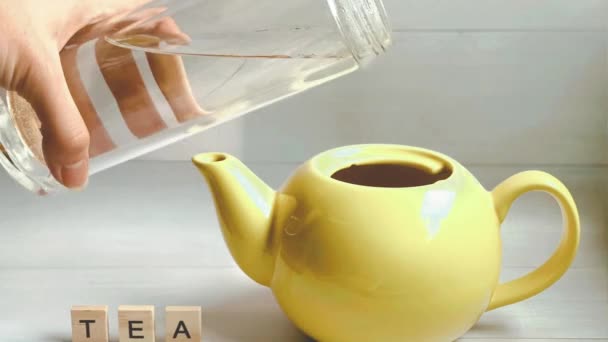 Stop-Motion-Animation, bei der der Prozess des Aufbrühens von Tee vor sich geht, Wasser in die gelbe Teekanne gegossen wird, dann eine Zitronenscheibe in die Teekanne fliegt und dann der Teebeutel und die Teekanne am Ende tanzen. - Filmmaterial, Video