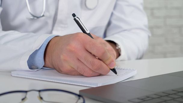 Lekarz pisze objawy w notebooku bada pacjenta online wideo rozmowy laptop - Zdjęcie, obraz