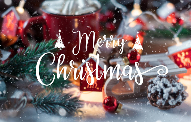 Veselý vánoční text se zimním horkým nápojem, kakao s marshmallows a skořicí nebo pikantní horkou čokoládou v červeném poháru a věnečnými světly. Slavnostní ročník blahopřání. - Fotografie, Obrázek