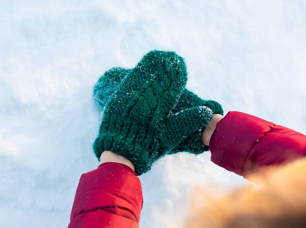 osoba s vlněnými zelenými rukavicemi na rukou. Dělat srdce. Přikryté sněhovými vločkami. Koncept zimního a vánočního času. Zavřít - Fotografie, Obrázek