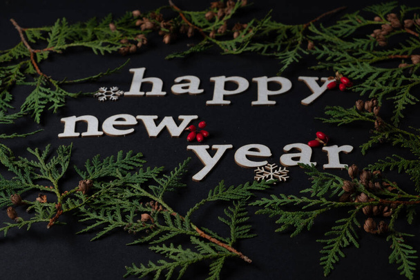 Happy new year inscription on black background. Green spruce branches and full frame. - Photo, Image