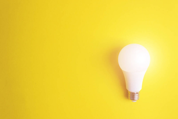 Hehkuva lamppu keltaisella pohjalla, ainutlaatuisuus käsite. Idea, innovaatio, luovuuskonsepti, suunnittelumalli, kopiotila - Valokuva, kuva