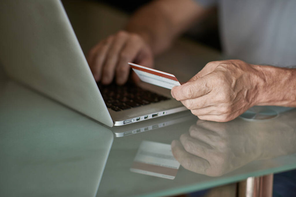 Hombre mayor Compras en línea con tarjetas de crédito en el ordenador portátil en la mesa - Foto, imagen