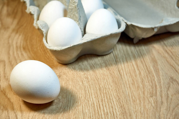 Сирі курячі яйця в картонній коробці на столі
 - Фото, зображення