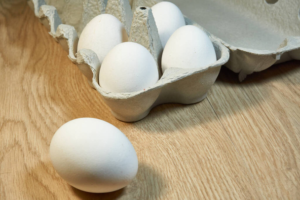 Surowe jaja kurze w kartonowym pudełku na stole. - Zdjęcie, obraz