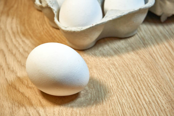 Сырые куриные яйца в картонной коробке на столе. - Фото, изображение