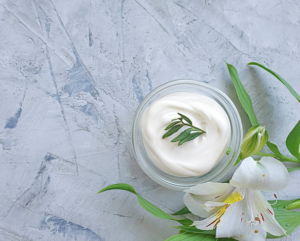 crema cosmética, flor sobre un fondo de hormigón - Foto, imagen