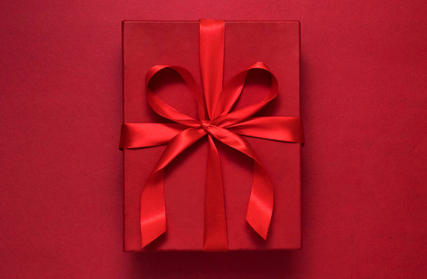 Punainen lahjapaketti punaisella taustalla punaisella nauhalla tervehdyskonsepti - Valokuva, kuva