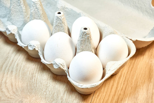 Huevos de pollo crudos en una caja de cartón sobre la mesa. - Foto, Imagen