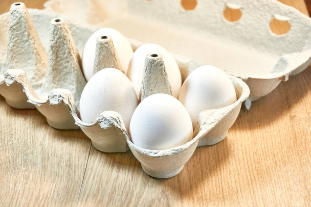 Syrová kuřecí vejce v lepenkové krabici na stole. - Fotografie, Obrázek