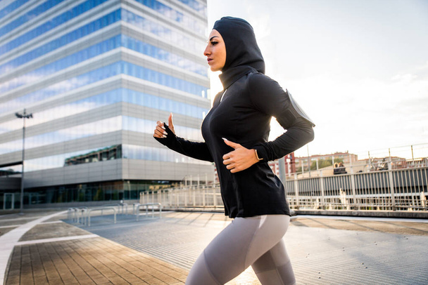 Muslim sportive girl with fit body training outside - Beautiful woman with hijab doing some sport exercises, concepts about health, lifestyle and functional training - Фото, зображення