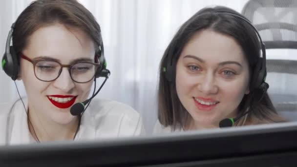 Imagen recortada de dos operadoras de call center femeninas con auriculares usando computadora - Imágenes, Vídeo