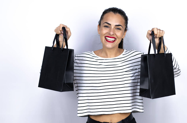 Fiatal, gyönyörű nő, fekete bevásárlótáskákkal a kezében, mosolyog. Fekete péntek - Fotó, kép