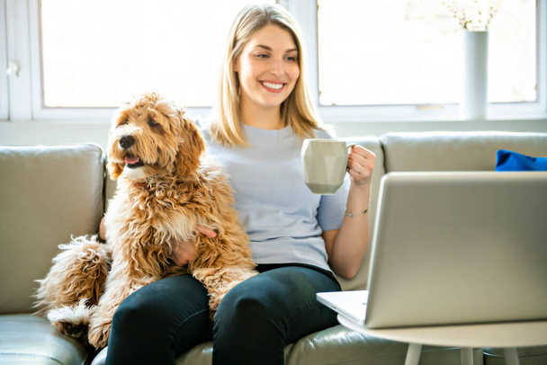 Frau mit ihrem Golden Labradoodle Hund zu Hause, der Kaffee trinkt - Foto, Bild