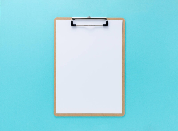 A wooden clipboard with white paper on a blue background - Photo, Image