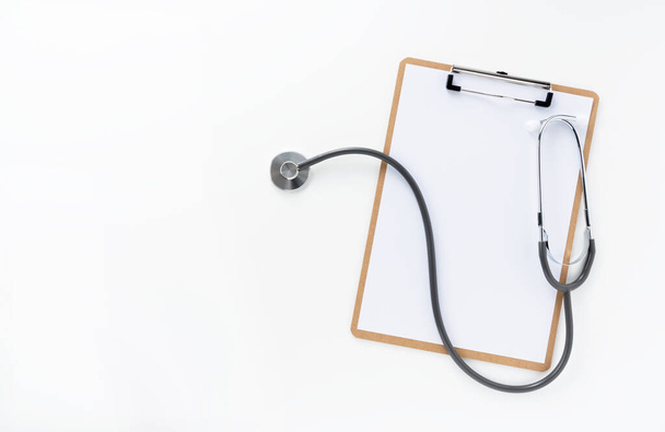 Ein Holzklemmbrett und Stethoskop mit weißem Papier auf weißem Hintergrund - Foto, Bild