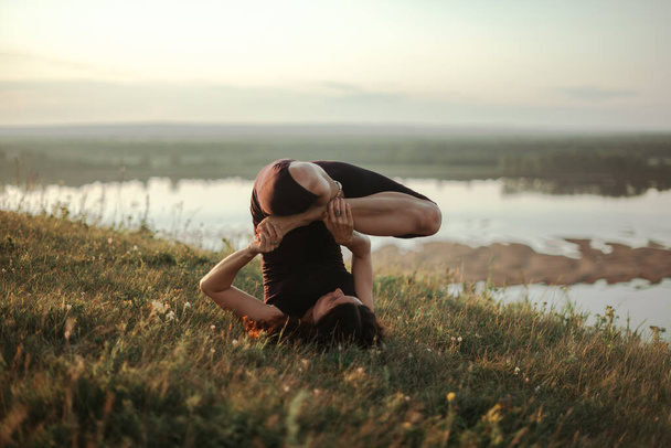 Praktyka jogi i medytacja w przyrodzie o wschodzie słońca. Kobieta ćwiczy w pobliżu wielkiej rzeki Kama. - Zdjęcie, obraz