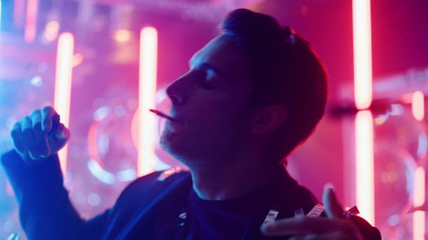 Rauhallinen mies puhaltaa savua klubilla. Rento kaveri tanssimassa konfetin alla juhlissa - Valokuva, kuva