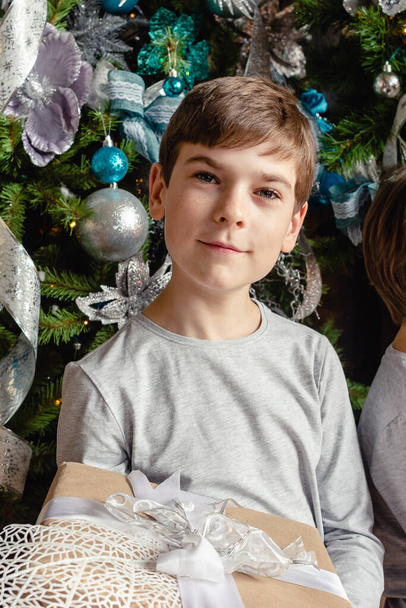 Smiling funny child in holding Christmas gift in hand. Christmas concept. Christmas time. - Valokuva, kuva