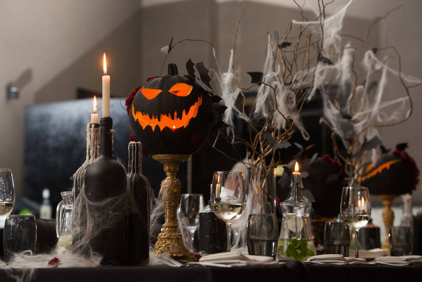 Table set for Halloween dinner. Served holiday table with candles and pumpkin. black tablecloth - Photo, Image