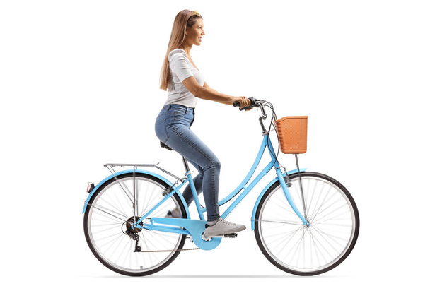 Full length profile shot of a young woman with long hair riding a bicycle isolated on white background - Foto, imagen