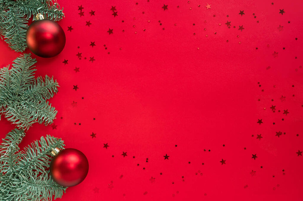 Kerst frame gemaakt van boomtakken, glitter en kerstballen op rood oppervlak. Vrolijk kerstfeest en gelukkig 2021 Nieuwjaarsconcept. Flat lay, bovenaanzicht, kopieerruimte - Foto, afbeelding