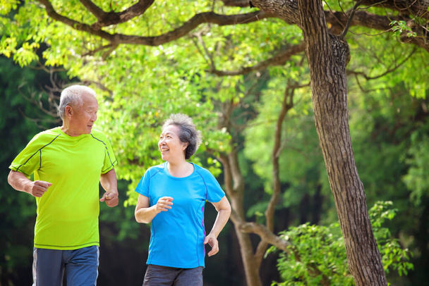 Joyeux couple sénior jogging dans le parc naturel - Photo, image