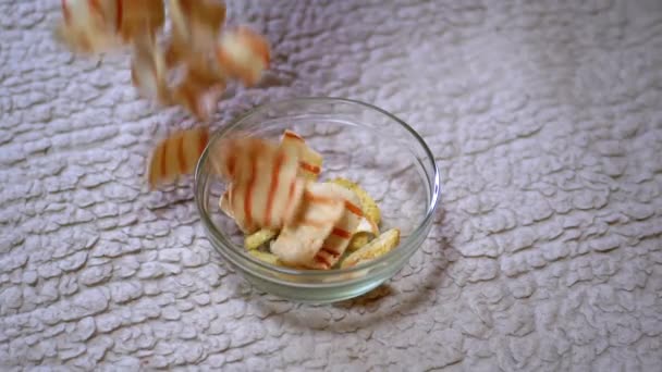 Patatine fritte croccanti appetitose che cadono in una ciotola e in un tavolo di vetro - Filmati, video