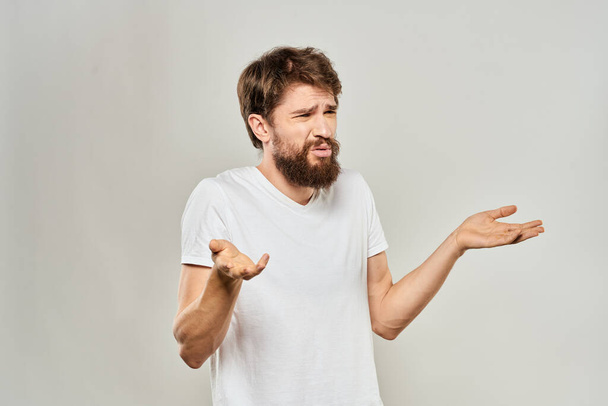 hombre en camiseta blanca gestos con sus manos estudio insatisfacción estilo de vida fondo claro - Foto, imagen